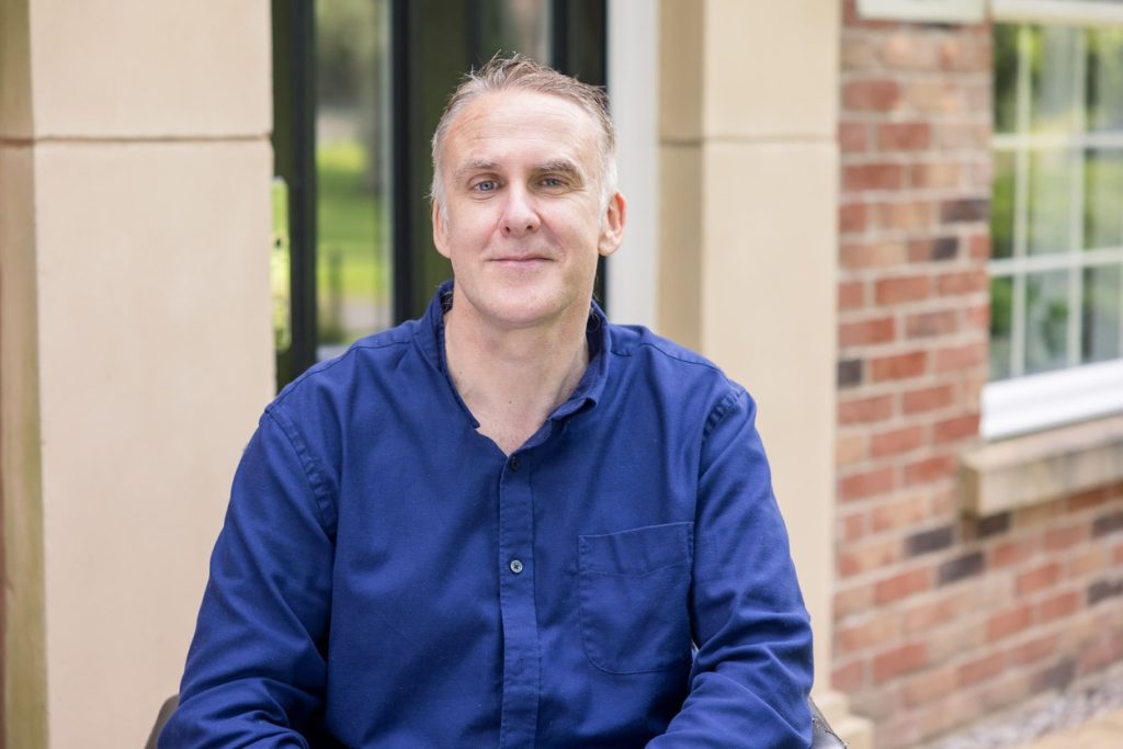 Image of a man in a blue shirt sitting outside a building
